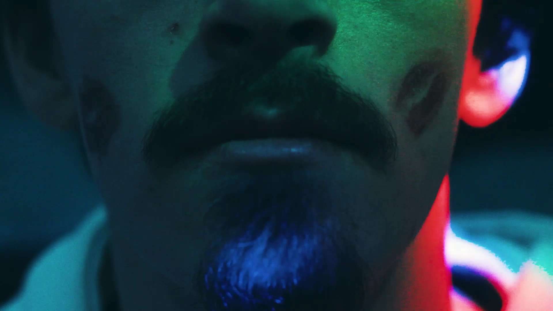 photo d'un homme avec des traces de rouge aa lèvre sur les joues dans un décor sombre avec des lumières festives