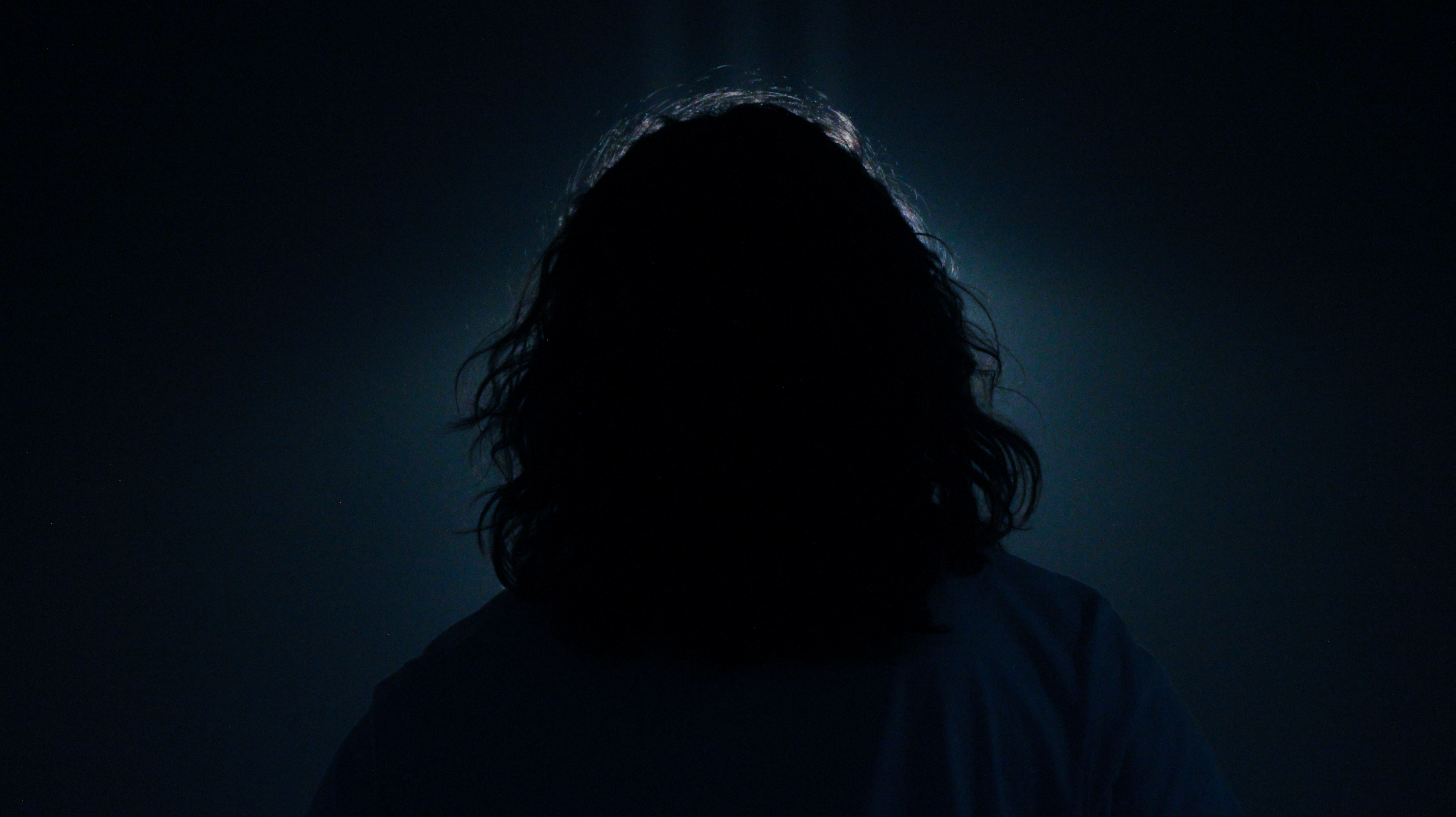 Photo de dos d'un homme face a une lumière bleu