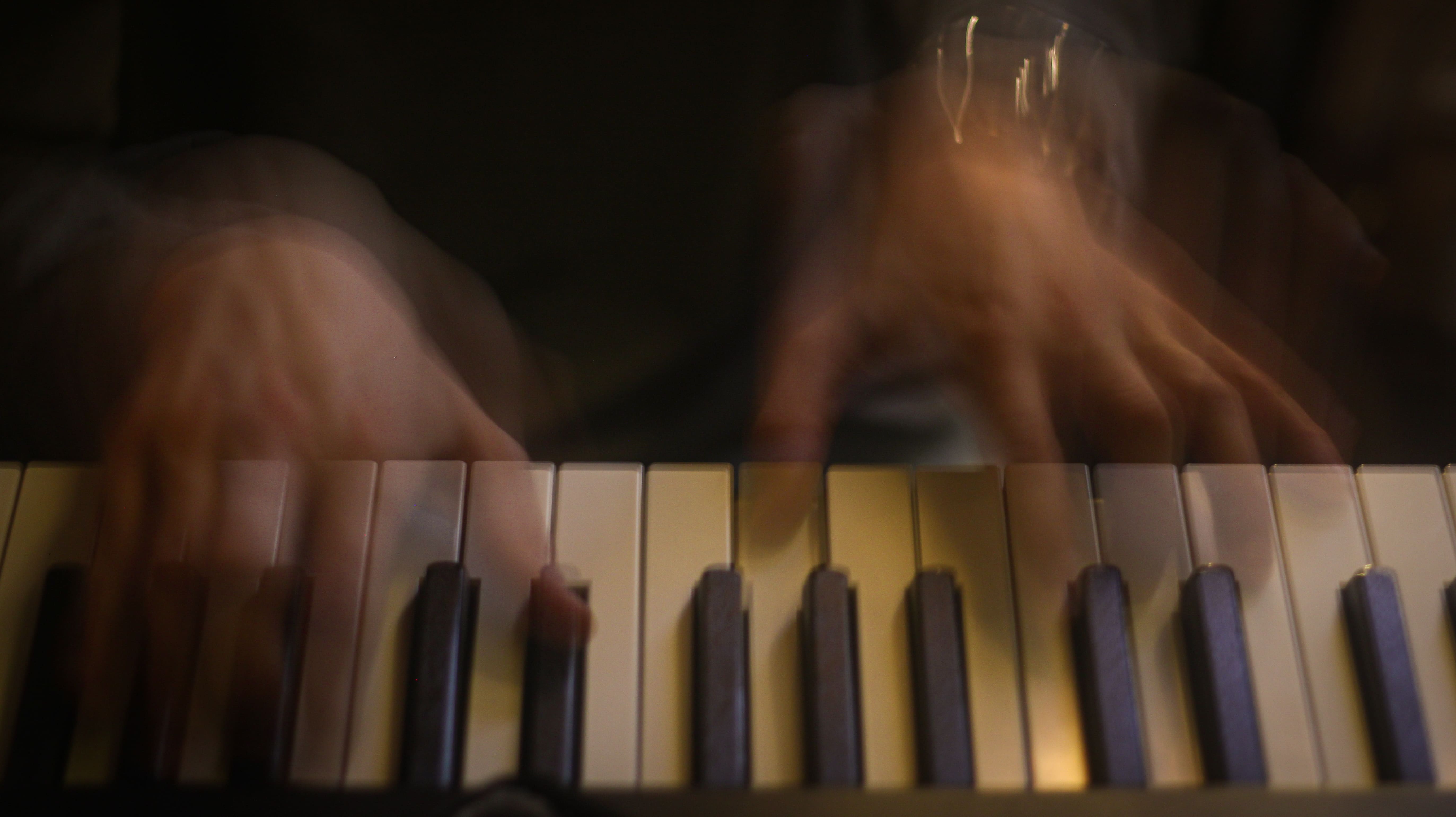 Photo d'un piano avec du flou de mouvement sur les mains du musiciens